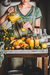 Young woman pouring fruit immune boosting drink to bottle