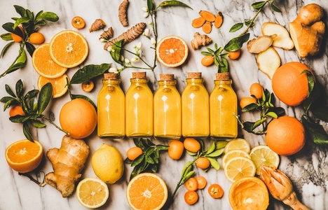 Turmeric  ginger  citrus juice shot in bottles over marble background
