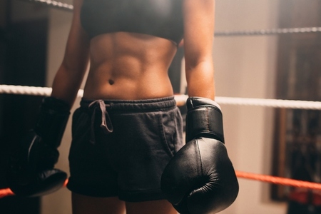 Woman with firm stomach muscles standing in a boxing ring