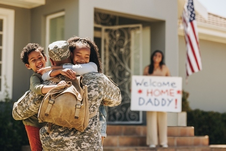 Cheerful children reuniting with their military dad