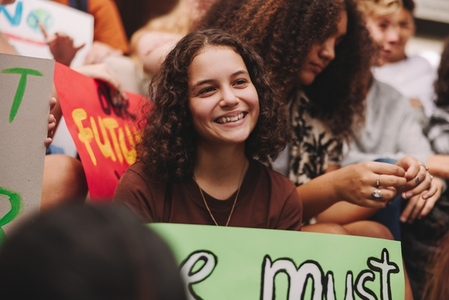 Happy teenage girl sitting with a crowd of climate change activists