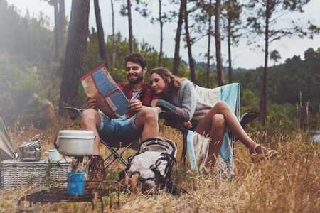 Young couple looking at a travel map while camping
