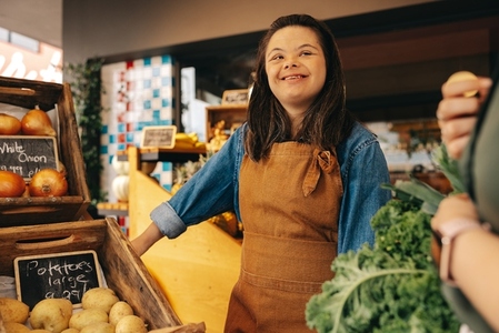 Happy woman with Down syndrome assisting a customer in a grocery store
