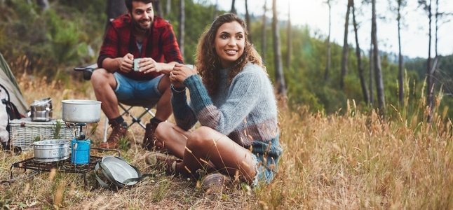 Cheerful young couple having coffee while camping