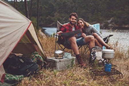 Loving couple reading a travel map while camping by the lake