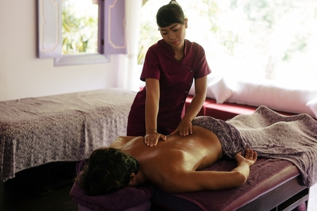 Female massage therapist massaging man at day spa