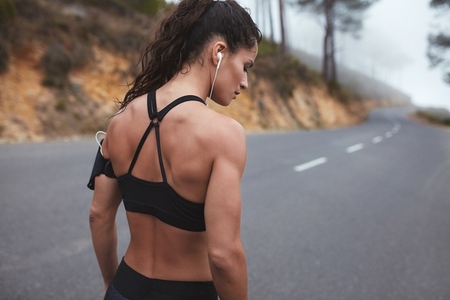 Female athlete with muscular body standing on a country road