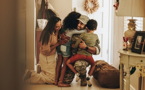 Cheerful army soldier reuniting with his family at home