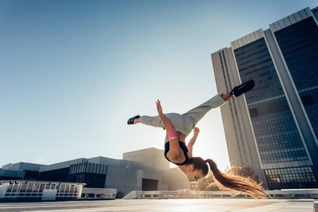 Woman doing frontflip outdoors in city