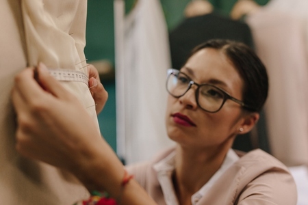 Fashion designer taking measurements on mannequin