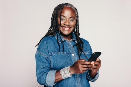 Happy mature woman smiling while holding a smartphone