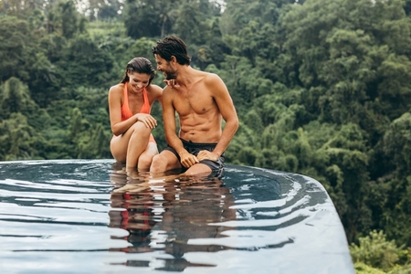 Young couple relaxing on the edge of pool