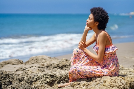 Black woman resting near waving sea