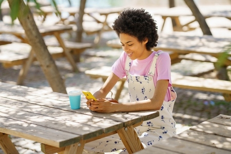Content black woman surfing cellphone at wooden table