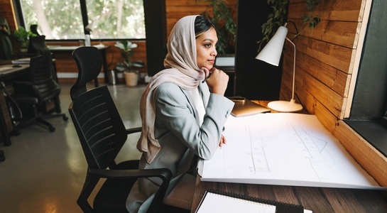 Contemplative Muslim designer working in an office
