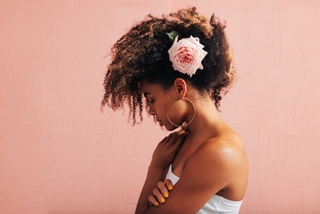 Side view of a young woman with pink flower in her curly hair