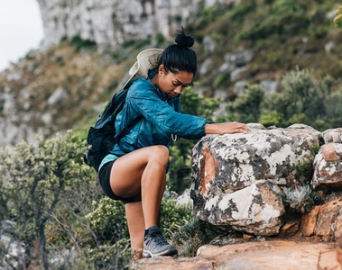 Young female in sportswear climbing up in wild terrain