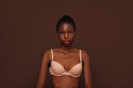 Portrait of a young woman in lingerie against brown background