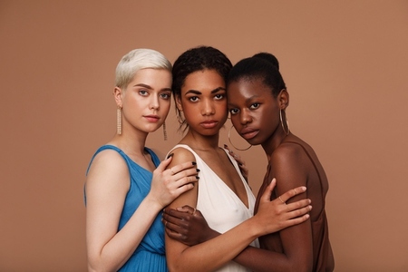 Three diverse women looking at camera  Young females with different skin tones standing together