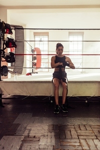 Woman wrapping her hands with black fabric in a boxing gym