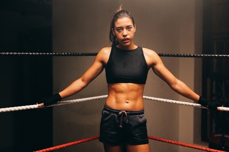 Fit young woman standing in one corner of a boxing ring