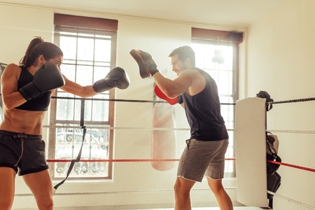 Female boxer training with her personal trainer at the gym