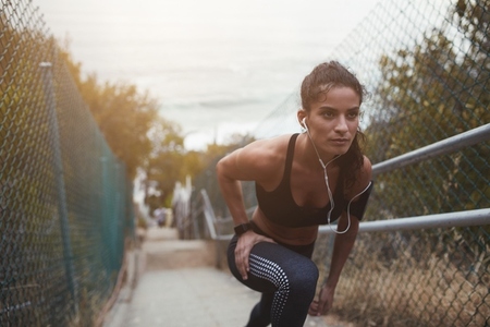 Female athlete doing stretch exercises on a staircase outdoors
