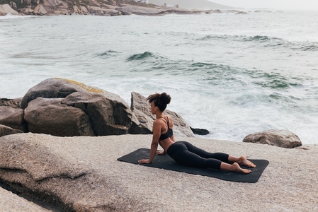 Female in cobra yoga pose at seaside  Woman in sportswear doing