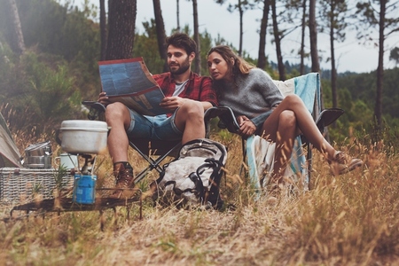 Young couple looking at a map while sitting at their campsite