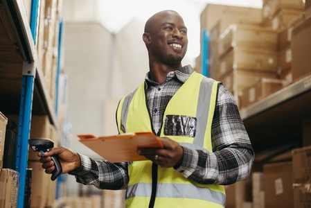 Happy warehouse manager scanning package labels with a barcode reader