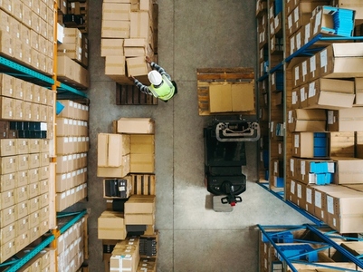 Top view of a warehouse worker moving package boxes in a logistics centre