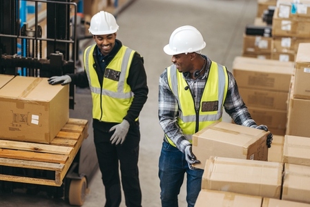 Happy logistics workers loading cardboard boxes onto a pallet truck
