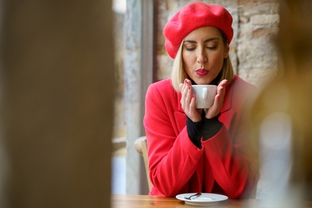 Woman blowing on hot coffee in cafe