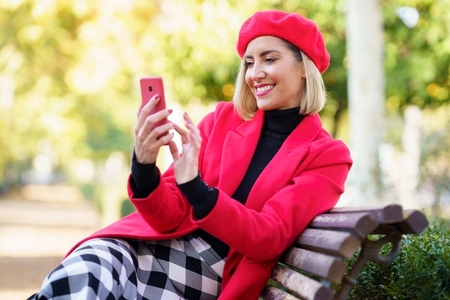 Cheerful woman browsing smartphone in park