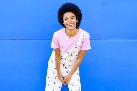 Smiling black woman standing near blue wall