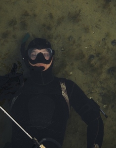 Spearfishing diver showing a thumbs up sign while lying in the water
