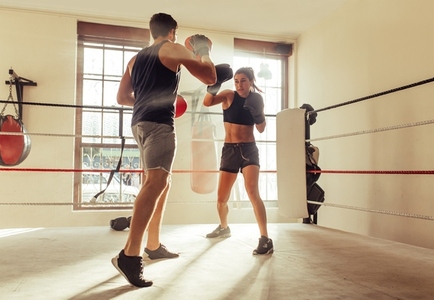 Trainer helping a female boxer with striking techniques