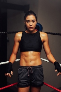 Female athlete standing in one corner of a boxing ring