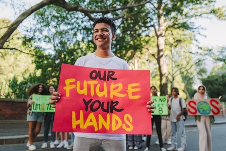 Cheerful teenage boy protesting at a climate change demonstration