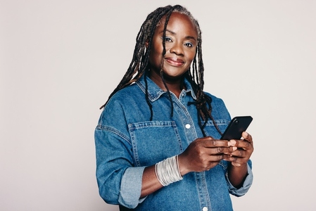 Beautiful black woman holding a smartphone in a studio