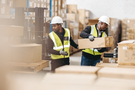 Two logistics workers offloading packages from a pallet truck
