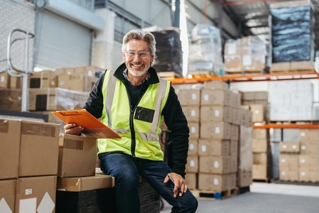 Happy senior man smiling at the camera in a distribution warehouse