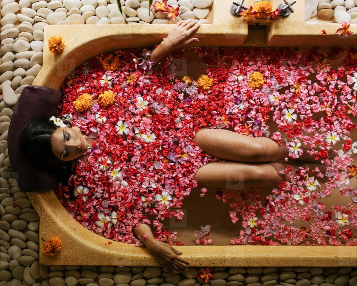 Woman taking flower bath at spa center