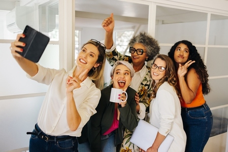 Cheerful businesspeople posing for a group selfie in an office