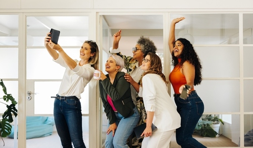 Cheerful businesspeople taking a group selfie in an office