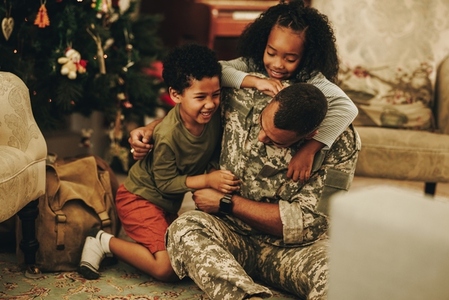 Army soldier playing with his kids at Christmas