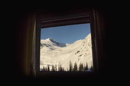 View of sunny snow covered mountain from cabin window