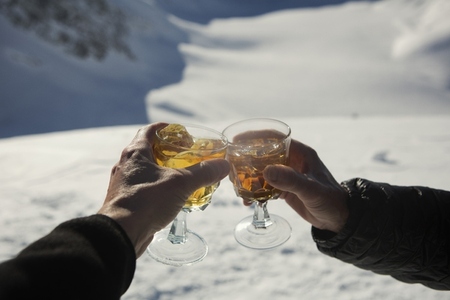 Close up POV hands of friends toasting apres ski cocktails in snow