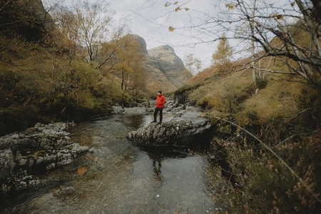 Man hiking on rock at idyllic autumn creek