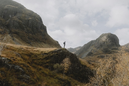 Hiker on rock in rugged autumn Scottish Highlands 2